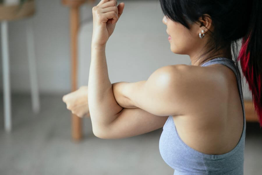 shoulders and arms workout, a woman is stretching her arm muscles